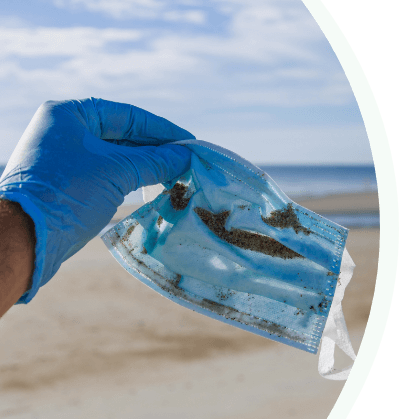 Dirty face mask being picked up by person wearing protective gloves